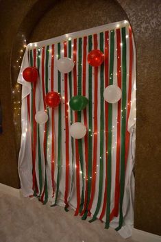 the wall is decorated with balloons and streamers in red, green and white stripes