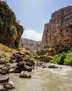 a river flowing through a canyon surrounded by rocky hills and trees in the distance,