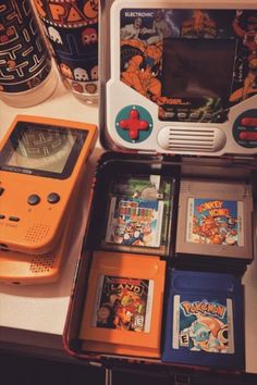 an orange gameboy sitting on top of a table next to other games and accessories