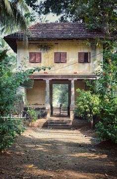 an old house in the middle of trees and dirt path leading up to it's entrance