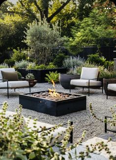 an outdoor fire pit surrounded by chairs and tables in the middle of a gravel area