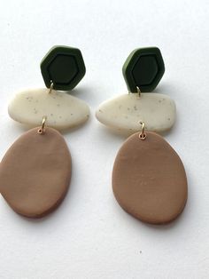 two brown and white earrings on top of each other, one with a green disc