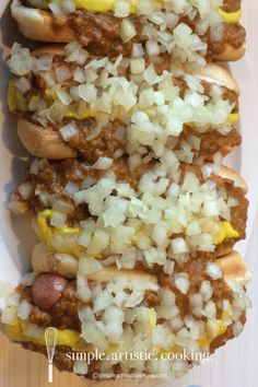 hot dogs with onions and mustard on a white plate