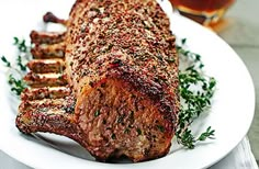 a piece of meat sitting on top of a white plate next to a glass of beer