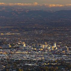 an aerial view of a city with mountains in the background and clouds in the sky