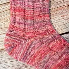 a pair of pink socks sitting on top of a wooden floor next to a red and white striped sock