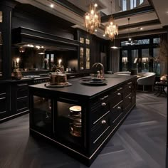 a large kitchen with black cabinets and chandeliers