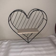 a heart shaped iron rack on top of a bed with white and gray stripped sheets