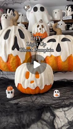 halloween pumpkins decorated with white and black icing, sitting on a table in front of fake ghost heads