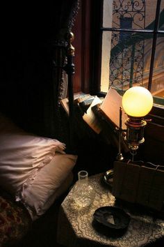 a lamp sitting on top of a table next to a bed in a dark room