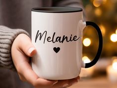 a person holding a coffee mug with the word melanie written in black on it