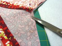 a pair of scissors sitting on top of a piece of fabric next to a cutting board