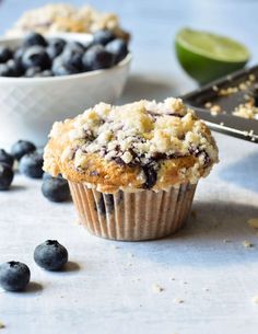 two blueberry muffins are sitting on a table next to some fresh blueberries