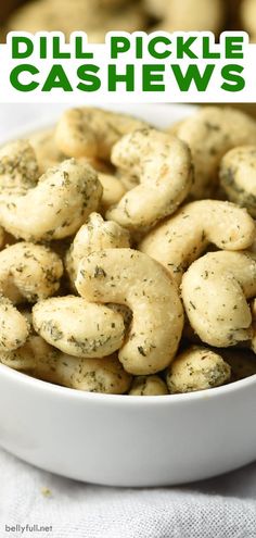 a white bowl filled with dill pickle cashews on top of a table