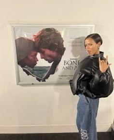 a woman standing in front of a movie poster giving the peace sign with her hand