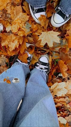 two people standing in leaves with their feet on the ground and one person wearing sneakers