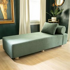 a gray couch sitting on top of a hard wood floor next to a mirror and window