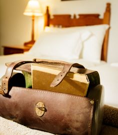 a suitcase sitting on the floor in front of a bed with white sheets and pillows