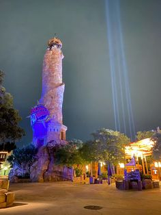 a tall tower sitting in the middle of a park with lights on it's sides