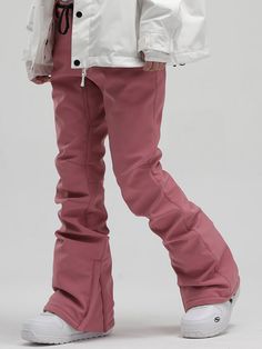 a person in white jacket and pink pants standing with their feet on the snowboard