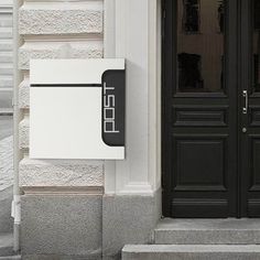 a black and white mailbox on the side of a building next to a door