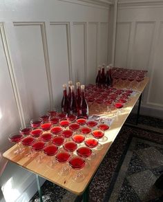 a long table with many wine glasses and bottles on it, all lined up in rows