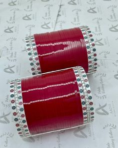 pair of red and silver cufflinks on white paper with embellished details