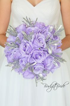 a bride holding a bouquet of purple roses and silver glittered leaves on her wedding day