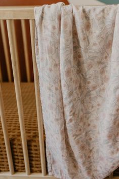 a baby's crib with a blanket draped over the top and bottom of it