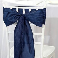 a chair with a blue bow tied to it's back sitting next to a white table