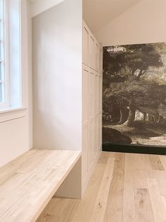 an empty room with wooden flooring and wallpaper on the walls, along with white cupboards