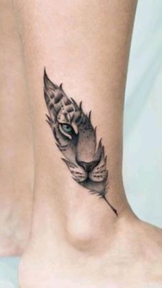 a cat's head with a feather tattoo on the ankle is shown in black and white