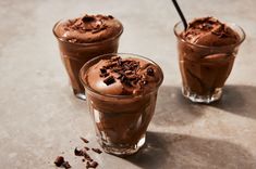 two glasses filled with chocolate ice cream on top of a table