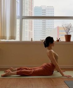 a woman is doing yoga in front of a window