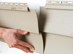 a person holding onto the side of a wall with siding tape on it and another hand reaching out