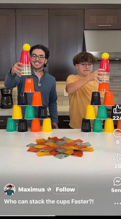 two men standing in front of a table with cups on it and one man pointing at them