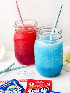 two mason jars filled with blue, red and white jello next to candy bars