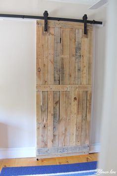 an open wooden door sitting on top of a hard wood floor next to a blue rug