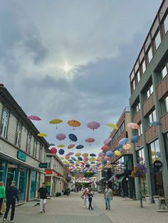 people walking down the street under umbrellas on a cloudy day