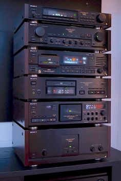 a stack of stereo equipment sitting on top of a table next to a wall mounted tv