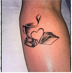 a tattoo on the leg of a woman with books and a cup