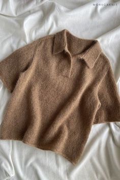 a brown sweater laying on top of a bed