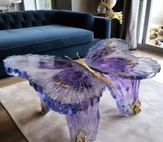 a purple butterfly shaped table sitting on top of a white rug next to a blue couch