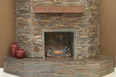 a stone fireplace with two red vases on the side and a brown wall behind it