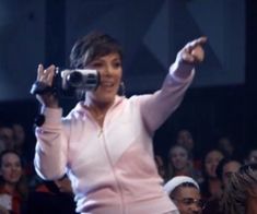 a woman holding a camera up to her face while standing in front of an audience