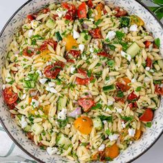 pasta salad with tomatoes, cucumbers, and feta cheese in a bowl