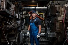 a man in overalls and work gloves standing next to machinery