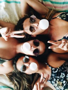 three women laying on top of each other wearing sunglasses and pointing fingers at the camera