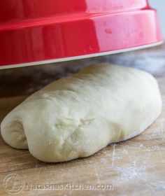 a piece of bread sitting on top of a wooden table next to a red bowl