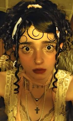 a close up of a person wearing necklaces and pearls on her head with eyes wide open